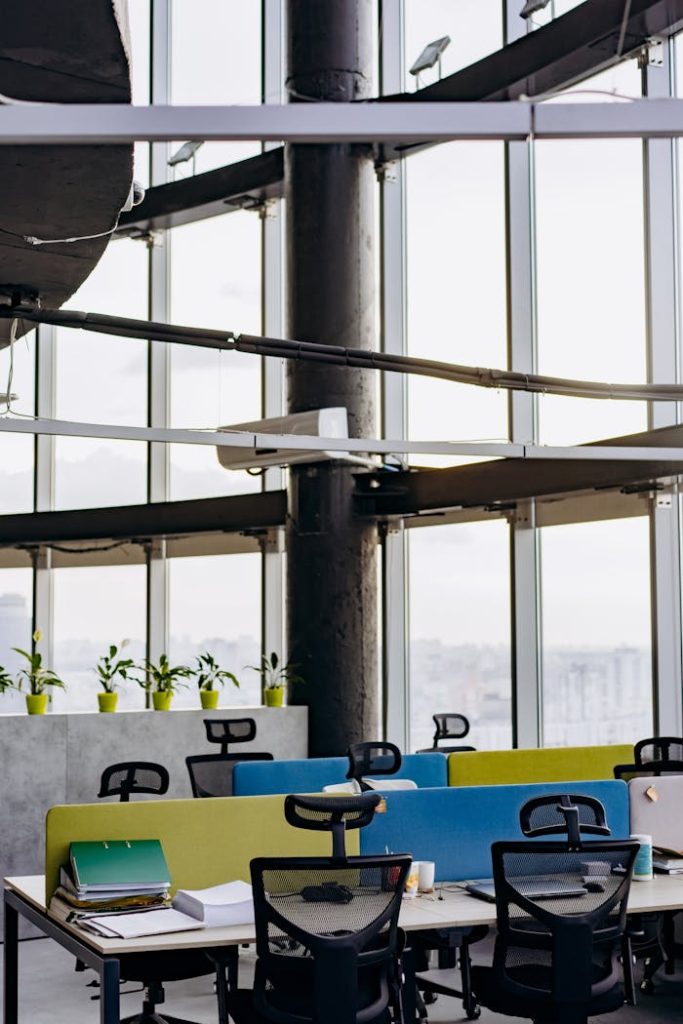 A spacious and modern office with large windows, colorful dividers, and potted plants creating a vibrant workspace.