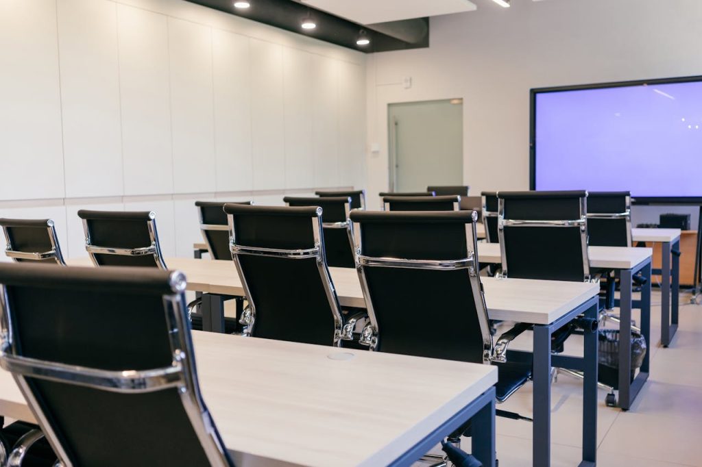 Spacious, modern conference room with black chairs and a projection screen.